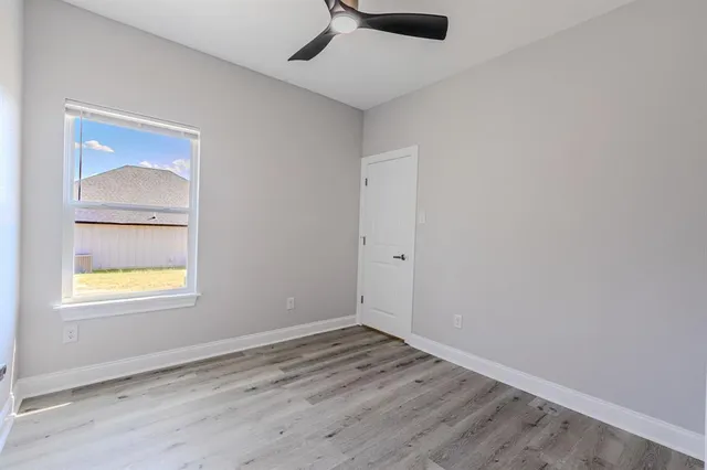 an empty room with a window and a ceiling fan