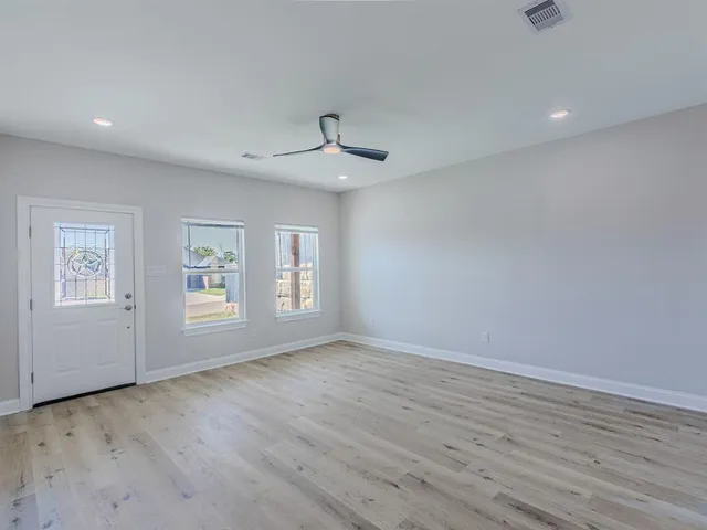 a view of an empty room with wooden floor and a window
