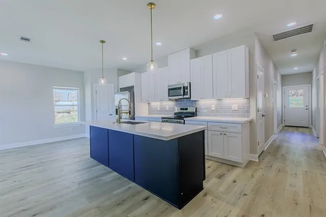 a kitchen with kitchen island granite countertop a sink refrigerator and wooden floor