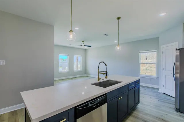 a kitchen with kitchen island a sink appliances and wooden floor