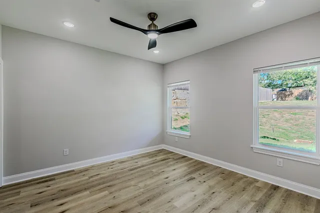 an empty room with wooden floor and windows