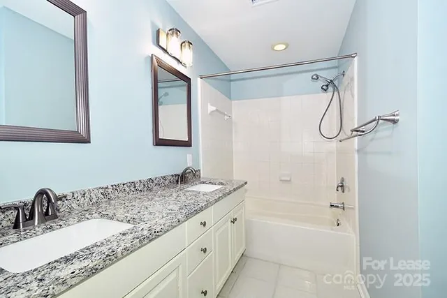 a bathroom with a granite countertop sink a mirror a shower and a bathtub