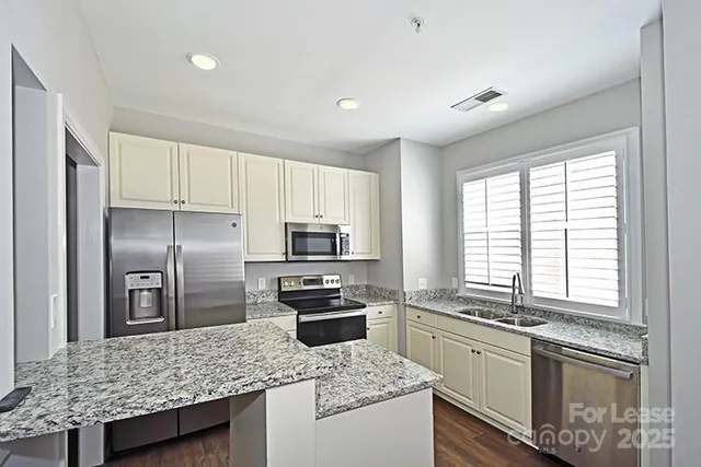 a kitchen with stainless steel appliances granite countertop a sink stove microwave and refrigerator
