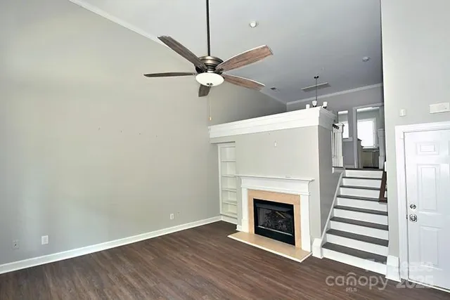 an empty room with wooden floor a fireplace a ceiling fan and wooden floor