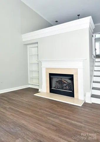 a view of an empty room with wooden floor fireplace and a window