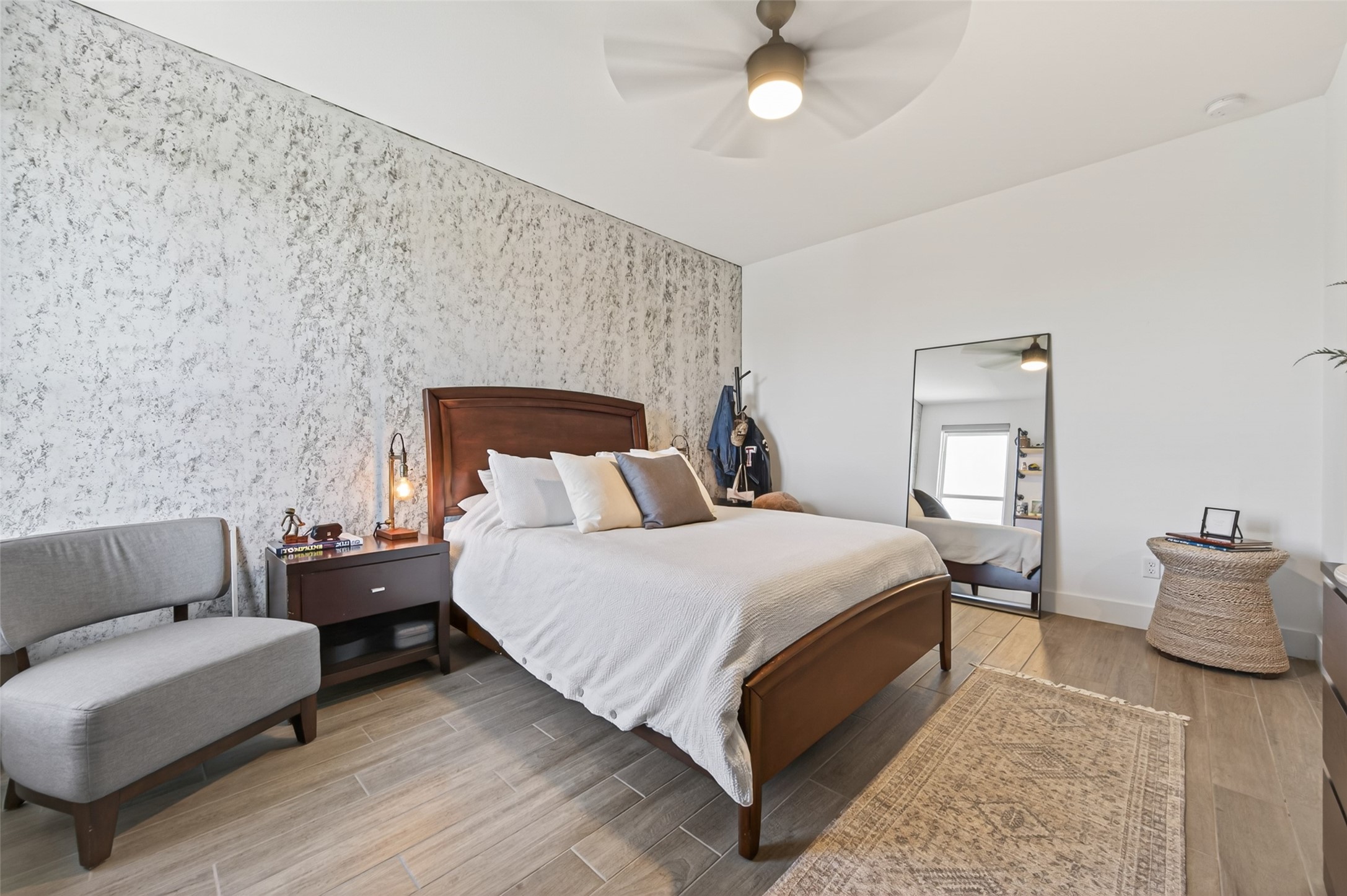 29612 Fulshear Lake Trace Fulshear, TX 77406 - Photo 43 of 48 This modern bedroom # 3 on the second floor, features a cozy bed with a wooden headboard, a stylish accent wall, and a ceiling fan for comfort. It includes a comfortable chair, a bedside table, a large mirror, and ample natural light. The room has a serene, contemporary design with neutral tones.
