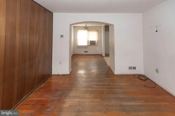 a view of a hallway with wooden floor and a bathroom