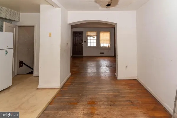 a view of a hallway to a livingroom with wooden floor and staircase