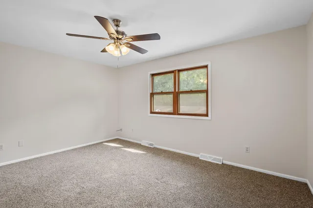 an empty room with a window and a ceiling fan