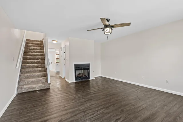 a view of an empty room with wooden floor fireplace and a window