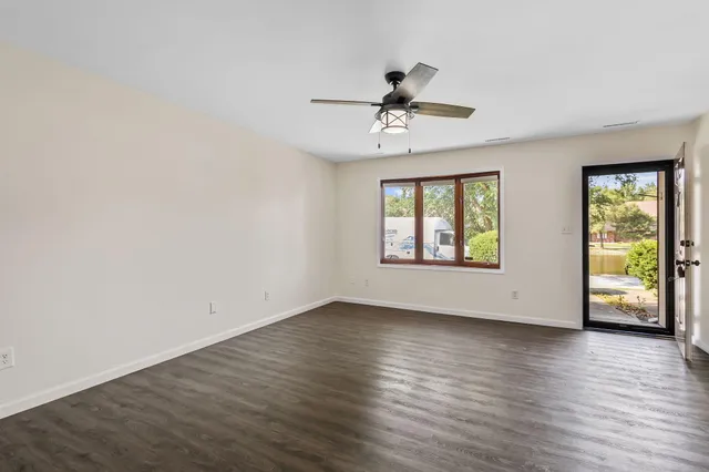 a view of an empty room with window and wooden floor