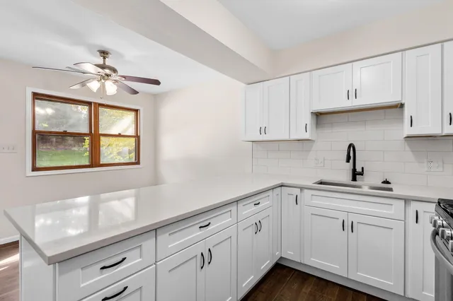 a kitchen with white cabinets appliances and a window