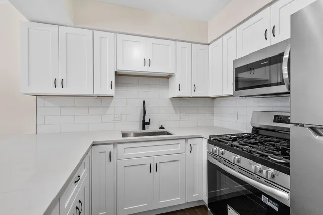 a kitchen with white cabinets and appliances