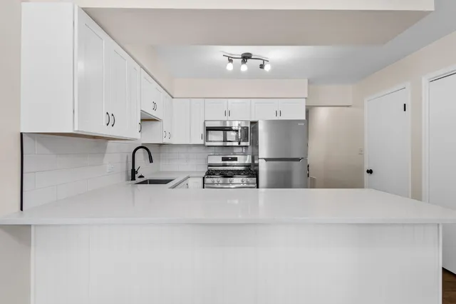 a kitchen with stainless steel appliances kitchen island a refrigerator sink and cabinets