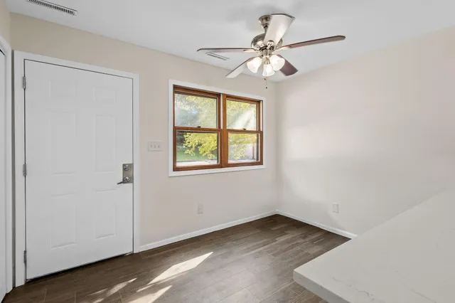 a view of an empty room with wooden floor and a window