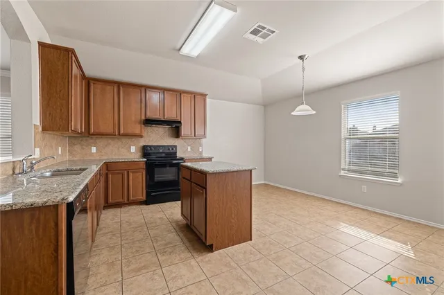 a kitchen with stainless steel appliances granite countertop a stove a sink a refrigerator and a granite counter tops