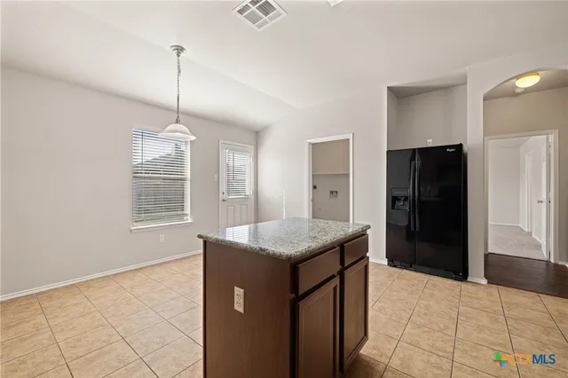 a kitchen with stainless steel appliances kitchen island granite countertop a refrigerator and a sink