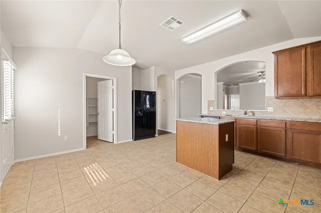 a kitchen with kitchen island granite countertop a refrigerator a sink and dishwasher