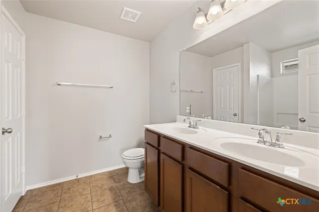 a spacious bathroom with a granite countertop sink a toilet and a mirror