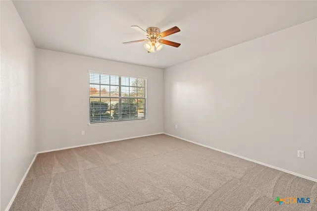 an empty room with windows and fan