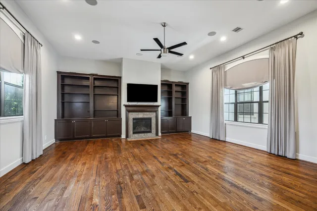an empty room with wooden floor cabinet and windows