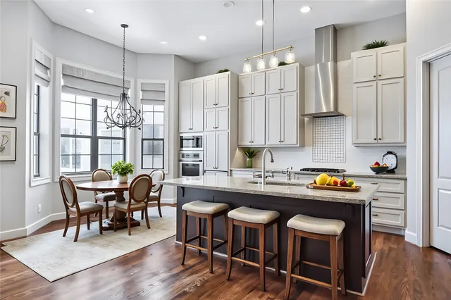 a view of an empty room with wooden floor and a kitchen