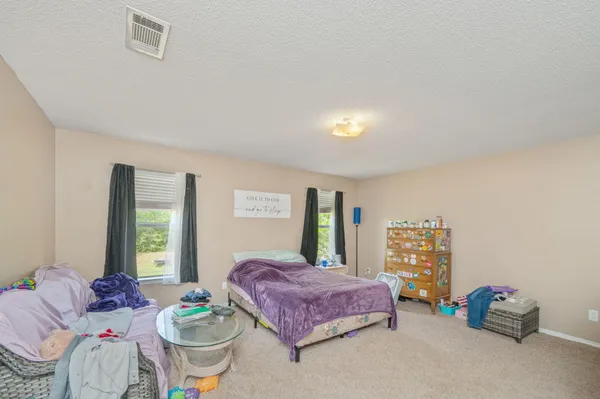 a spacious bedroom with a bed and wooden floor