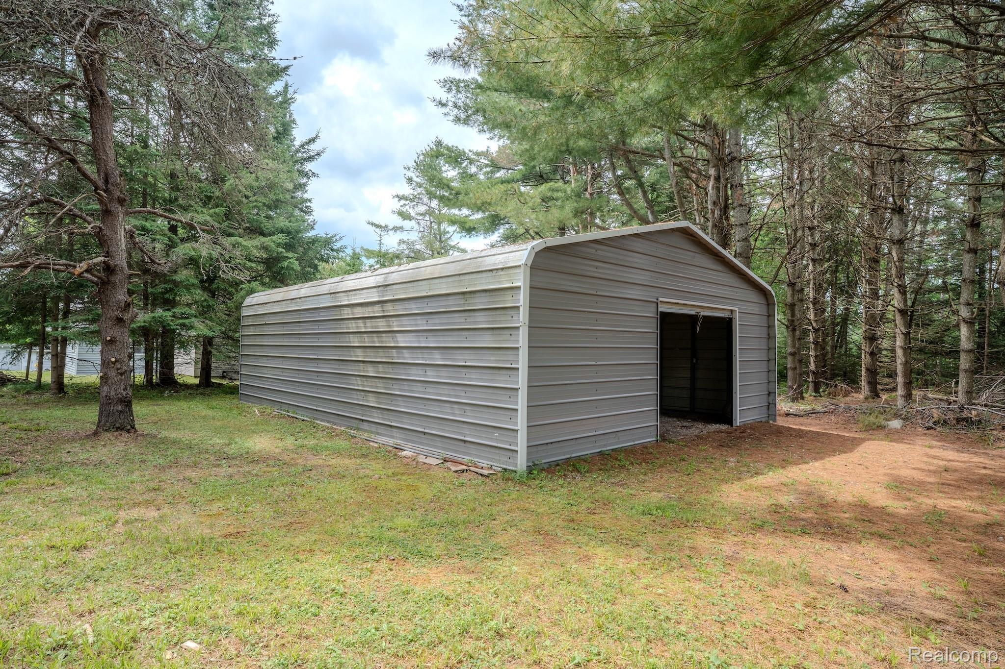 4350 Shrew Road Lincoln, MI 48742 - Photo 5 of 32 Metal storage structure featuring a roll-up door, corrugated siding, and a rounded roofline