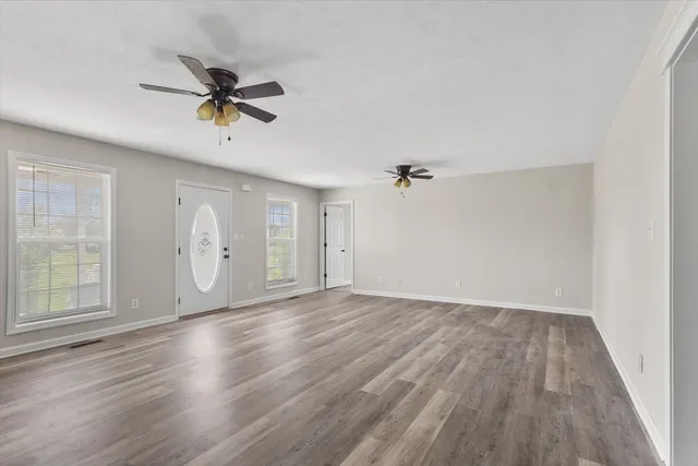an empty room with wooden floor and windows