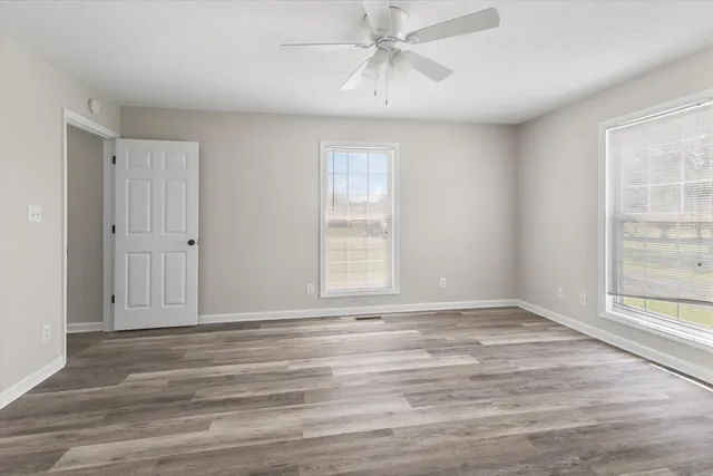 a view of an empty room with wooden floor and a window