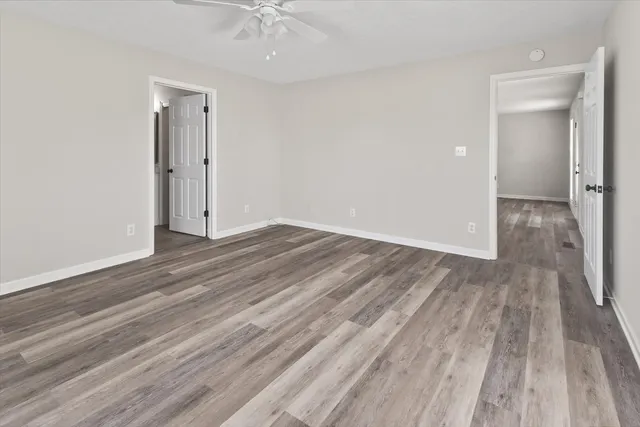 an empty room with wooden floor and a ceiling fan