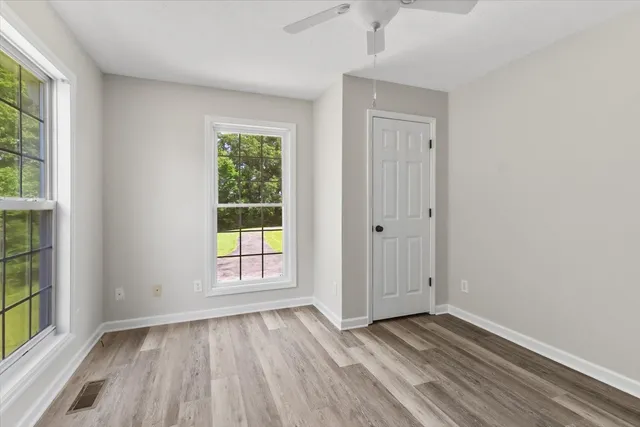 an empty room with wooden floor and windows