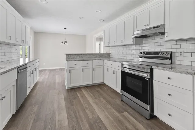 a kitchen with cabinets wooden floor and stainless steel appliances
