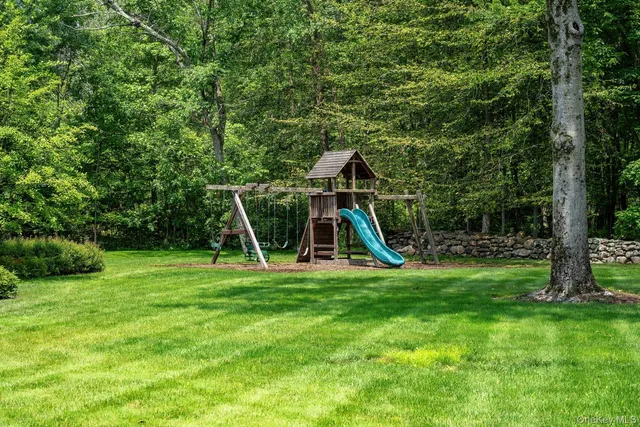 a view of a backyard with a slide trees and wooden fence