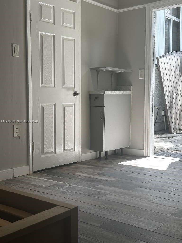 6837 Southwest 39th Terrace, Unit B Miami, FL 33155 - Photo 9 of 16 a view of an empty room with wooden floor and a kitchen