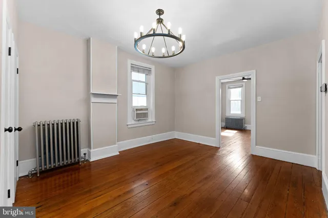 an empty room with wooden floor windows and white walls