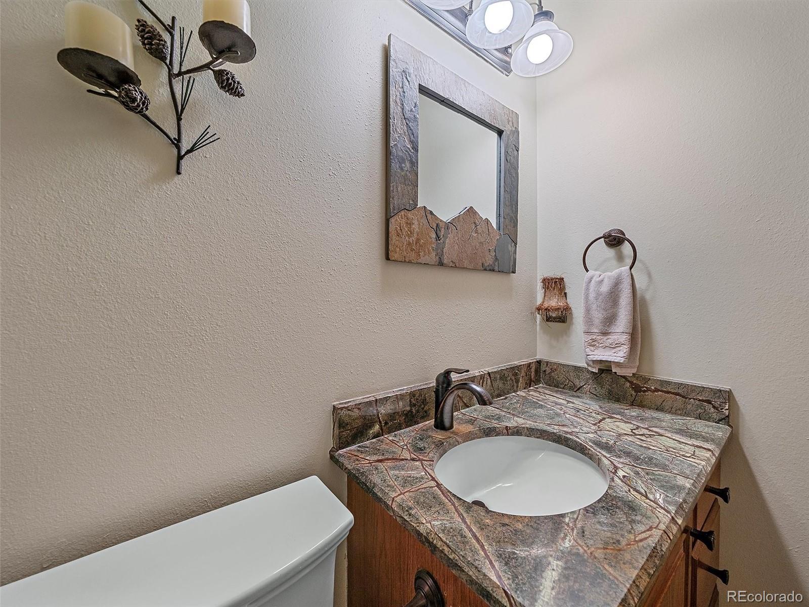 31412 North Bermuda Dunes Drive Evergreen, CO 80439 - Photo 21 of 46 a bathroom with a granite countertop sink a mirror and vanity