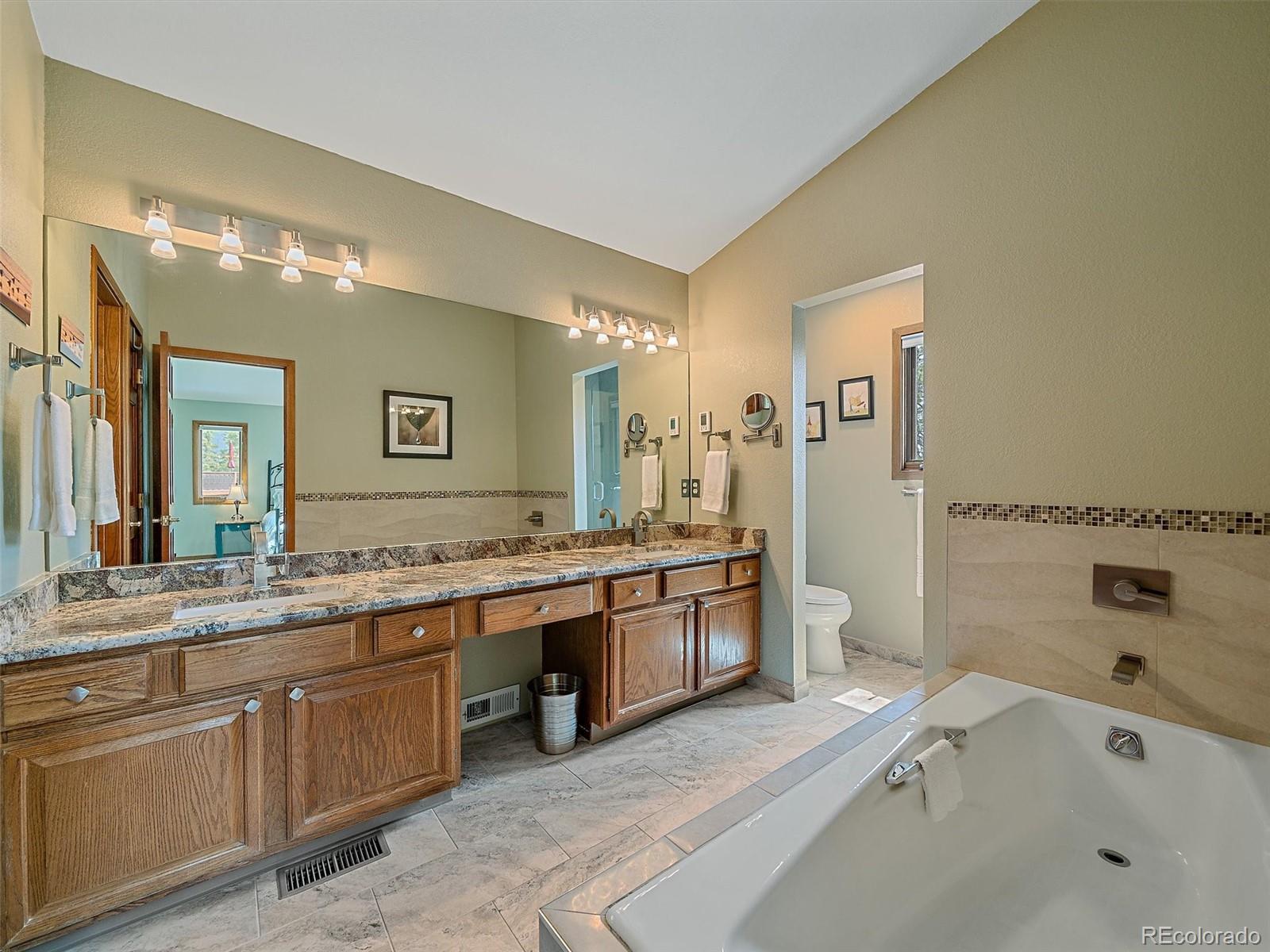 31412 North Bermuda Dunes Drive Evergreen, CO 80439 - Photo 26 of 46 a spacious bathroom with a granite countertop tub sink and mirror