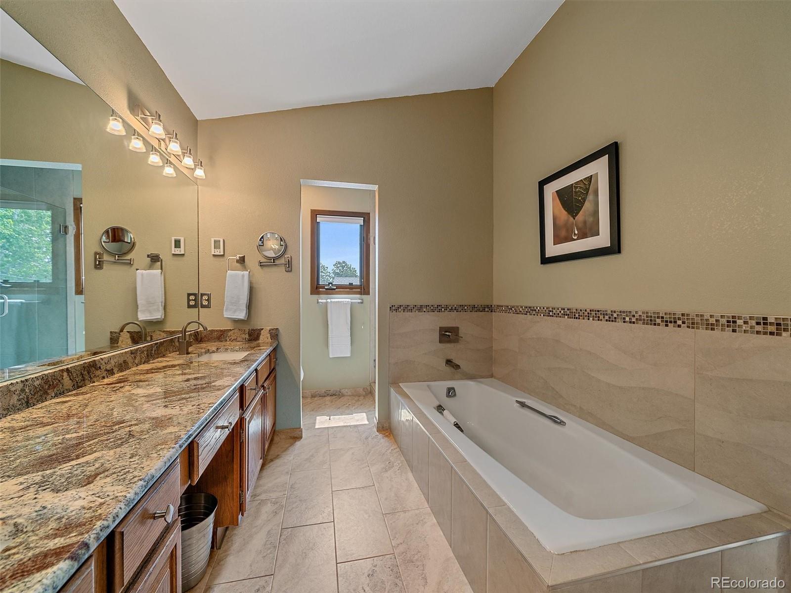 31412 North Bermuda Dunes Drive Evergreen, CO 80439 - Photo 27 of 46 a spacious bathroom with a granite countertop tub a double vanity sink and a mirror