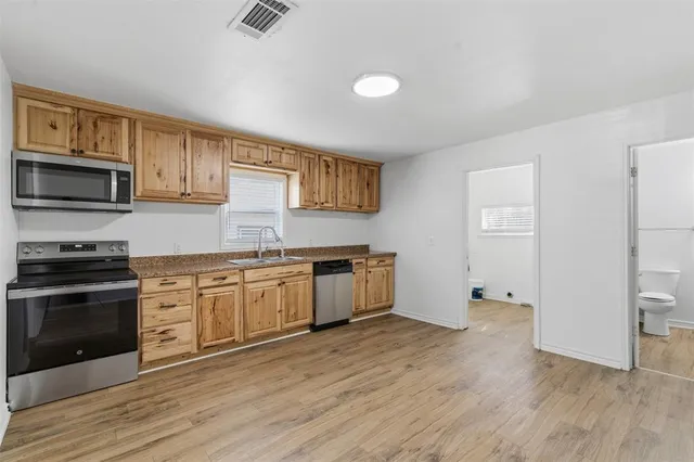 a kitchen with granite countertop a stove top oven a sink dishwasher and a refrigerator with wooden floor