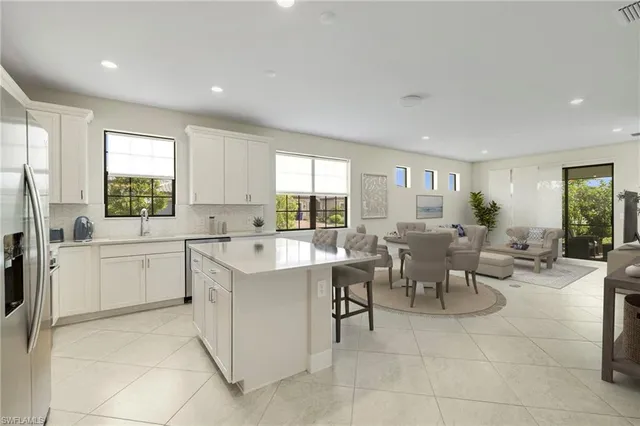 a large white dining hall with stainless steel appliances granite countertop furniture and a large window