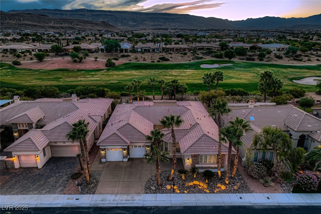 5015 Rivedro Street Las Vegas, NV 89135 - Photo 2 of 63 This sweeping aerial view showcases the front of the property in full scale, with the 15th hole of Siena Golf Club unfolding just beyond. Framed by the dramatic Sierra Nevada Mountains in the distance, the scene blends luxury living with breathtaking natural beauty.
