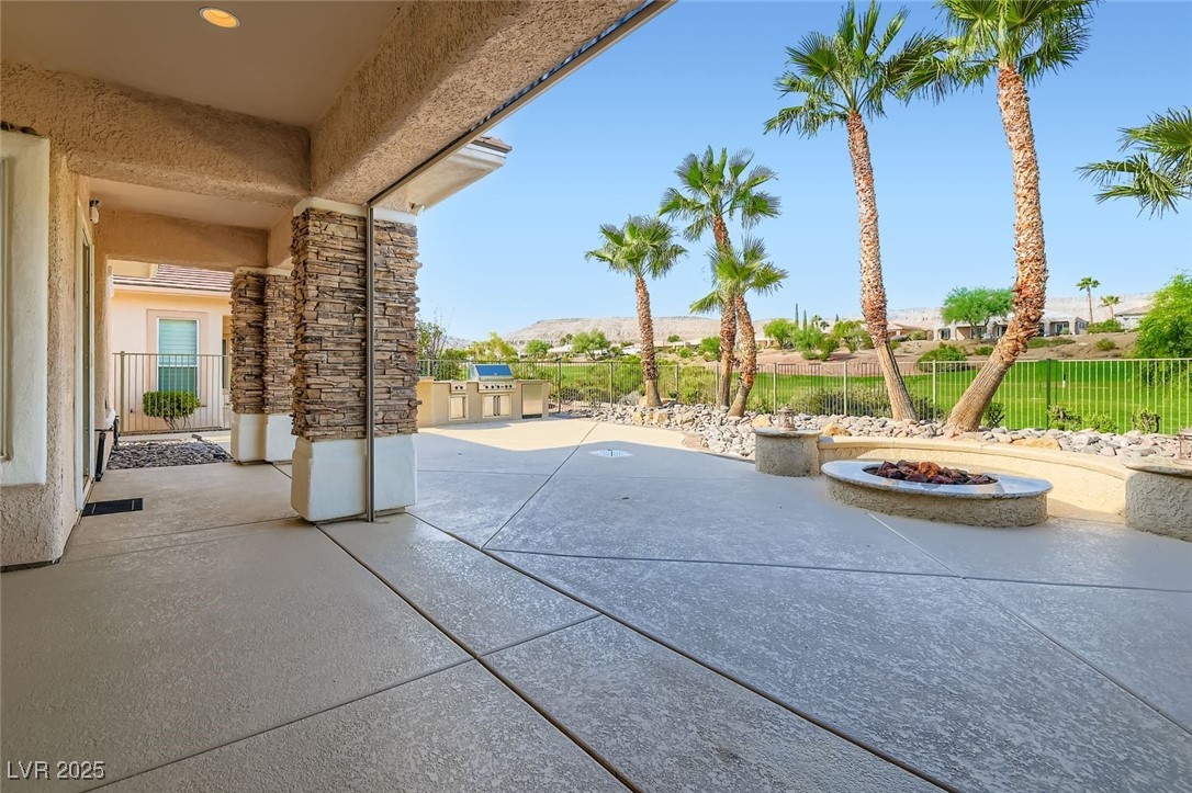 5015 Rivedro Street Las Vegas, NV 89135 - Photo 27 of 63 This stunning patio view showcases the gas fire pit and outdoor kitchen, framed by refreshed landscaping and elegant stone accents. Beyond, the breathtaking panorama of the 15th fairway at Siena Golf Course and the majestic Sierra Nevada Mountains creates a truly unforgettable backdrop for outdoor living.