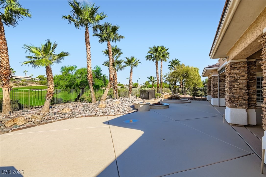 5015 Rivedro Street Las Vegas, NV 89135 - Photo 29 of 63 This perspective reveals the harmonious blend of spool, fire pit, and outdoor kitchen, all framed by lush landscaping and elegant stone pillars. The panoramic views of the golf course and Sierra Nevada Mountains elevate this terrace into a true sanctuary of desert luxury.