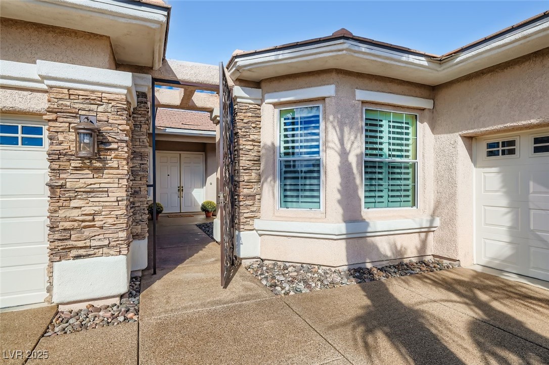 5015 Rivedro Street Las Vegas, NV 89135 - Photo 3 of 63 This gated front entrance showcases a harmonious blend of stone and stucco siding, complemented by a reglazed and stained Pebble Tec driveway and walkway. The entry’s craftsmanship and texture set the tone for elevated desert living with timeless curb appeal.
