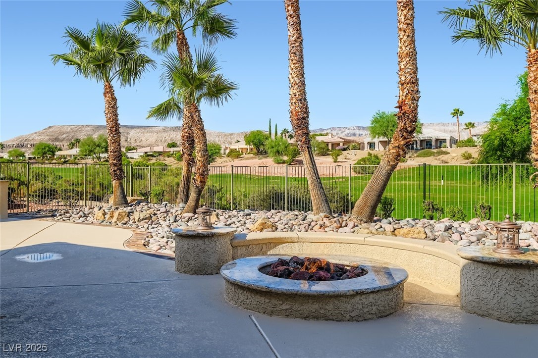 5015 Rivedro Street Las Vegas, NV 89135 - Photo 30 of 63 Step outside to a beautifully framed patio with the gas fire pit in the foreground, inviting cozy evenings under the stars. Beyond, a sweeping panoramic view of the golf course and Sierra Nevada Mountains delivers a daily dose of natural splendor and serenity.
