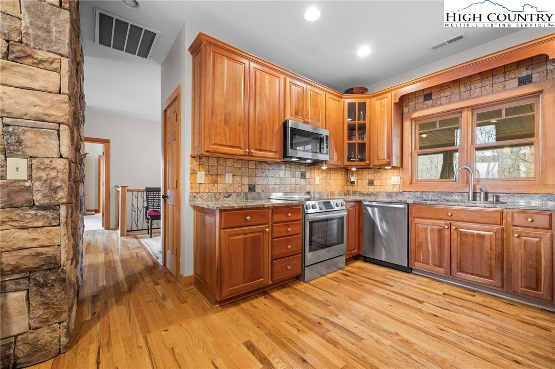 1690 Evergreen Drive Boone, NC 28607 - Photo 13 of 47 a large kitchen with stainless steel appliances granite countertop a stove a sink dishwasher a microwave oven with cabinets and wooden floor