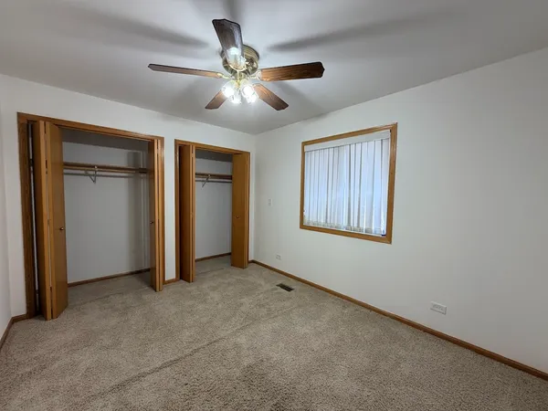 a view of an empty room with chandelier fan