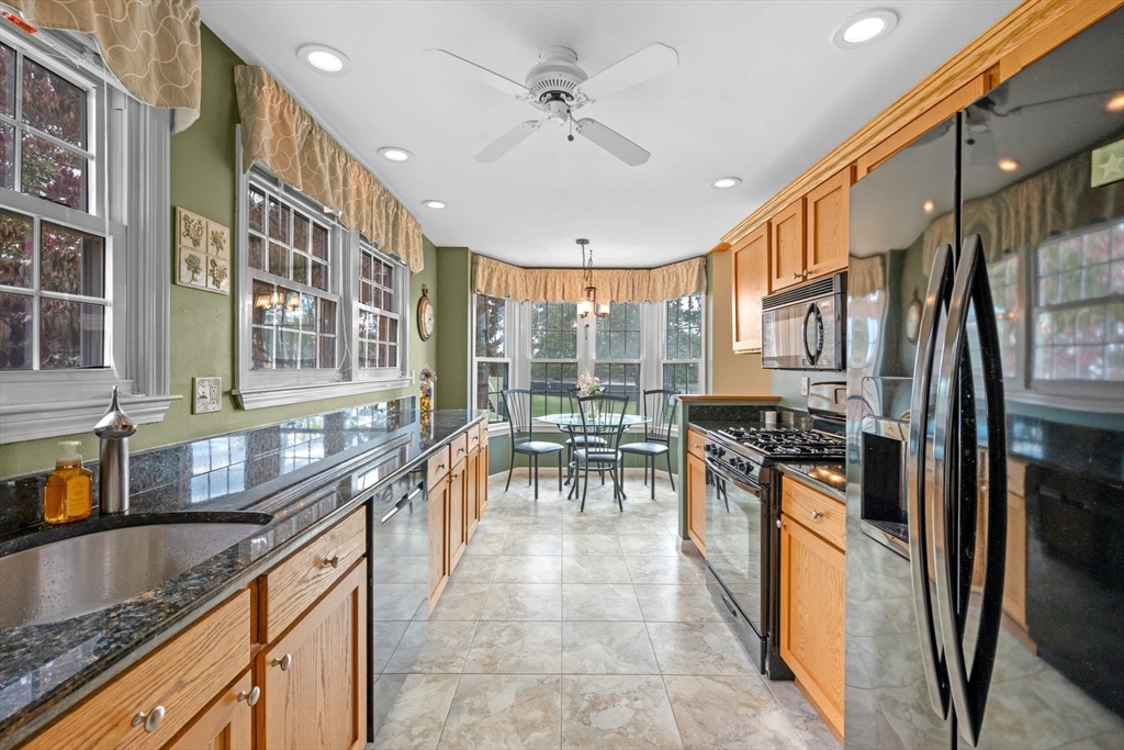 33 Water Street, Unit 7 Danvers, MA 01923 - Photo 6 of 35 a kitchen with stainless steel appliances granite countertop a stove top oven a refrigerator a sink and a dining table with wooden floor
