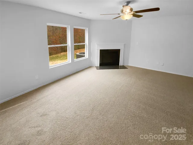an empty room with windows and fireplace